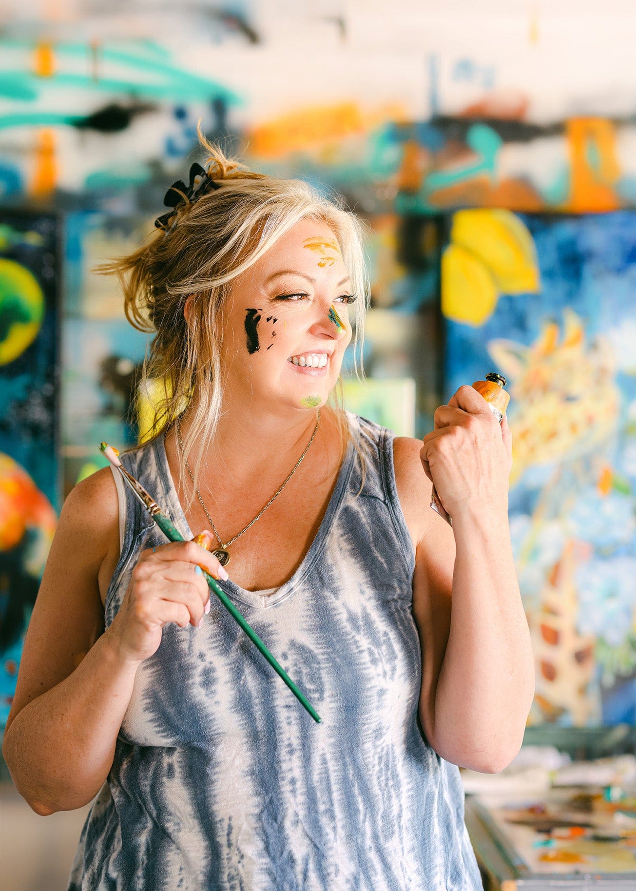 Woman with face paint holding a paintbrush in an art studio